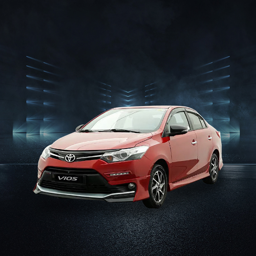 Red Toyota Vios sedan with sport body kit and alloy wheels, studio front-side view.