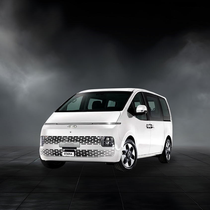 White Hyundai Staria MPV with futuristic grille design on a dark studio background.